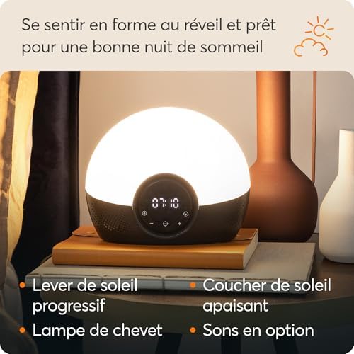 La lampe est posée sur une table de chevet avec des accessoires (livre, vase).