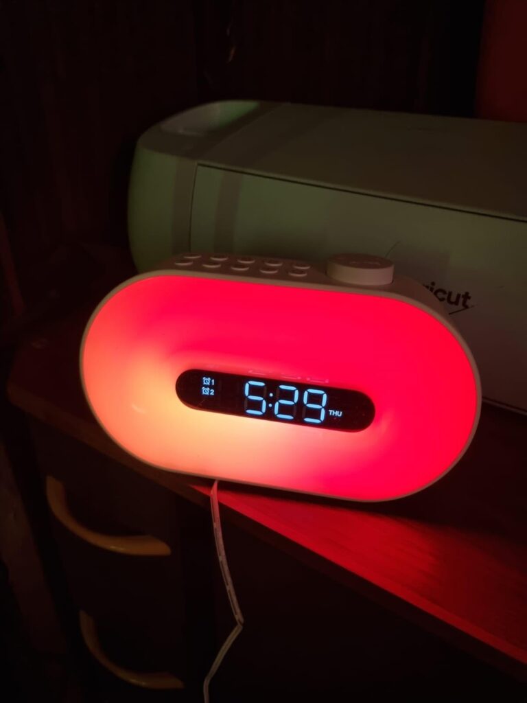 Le radio-réveil dans l'obscurité, affichant l'heure, avec un halo lumineux rouge.