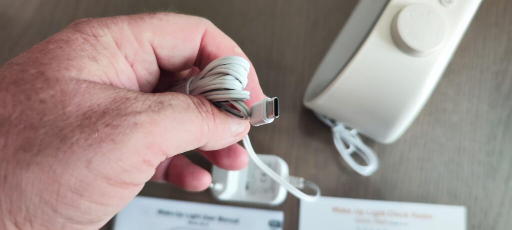 Gros plan sur le câble USB-A vers USB-C fourni avec le produit, tenu par une main.