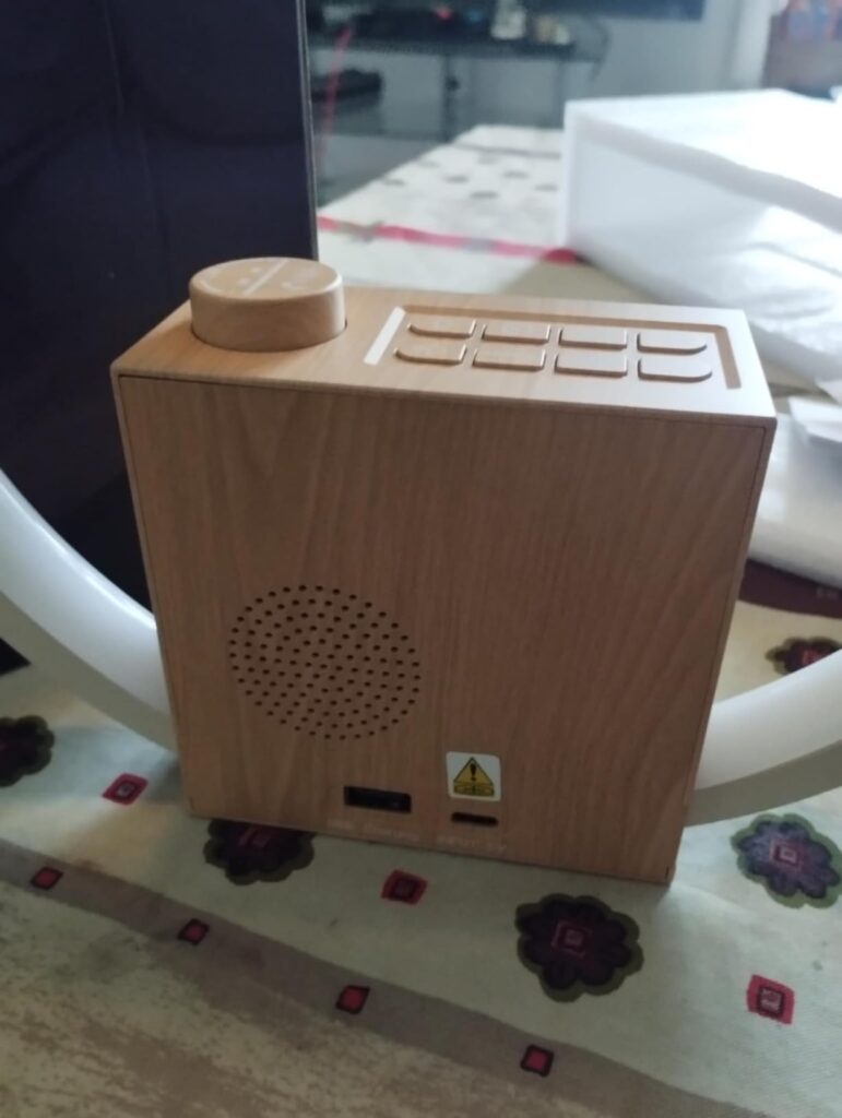 Vue arrière du réveil-matin en bois, montrant les haut-parleurs, les ports USB et les boutons de contrôle.