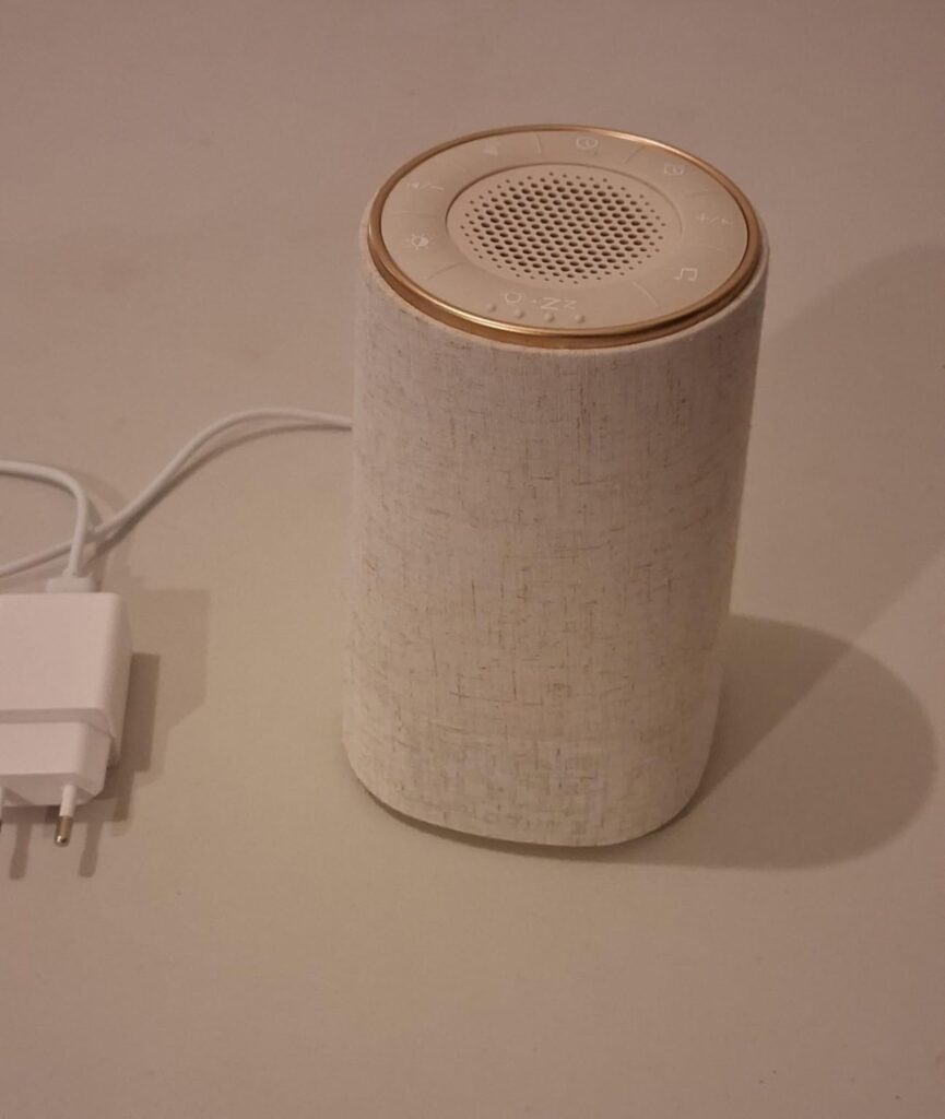 Vue latérale du produit avec son adaptateur secteur, posé sur une surface blanche.