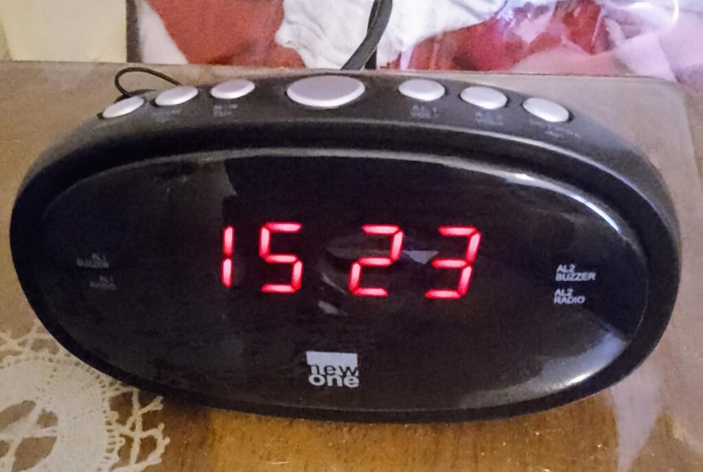 Gros plan sur l'écran du radio-réveil affichant l'heure, les boutons supérieurs et la marque.