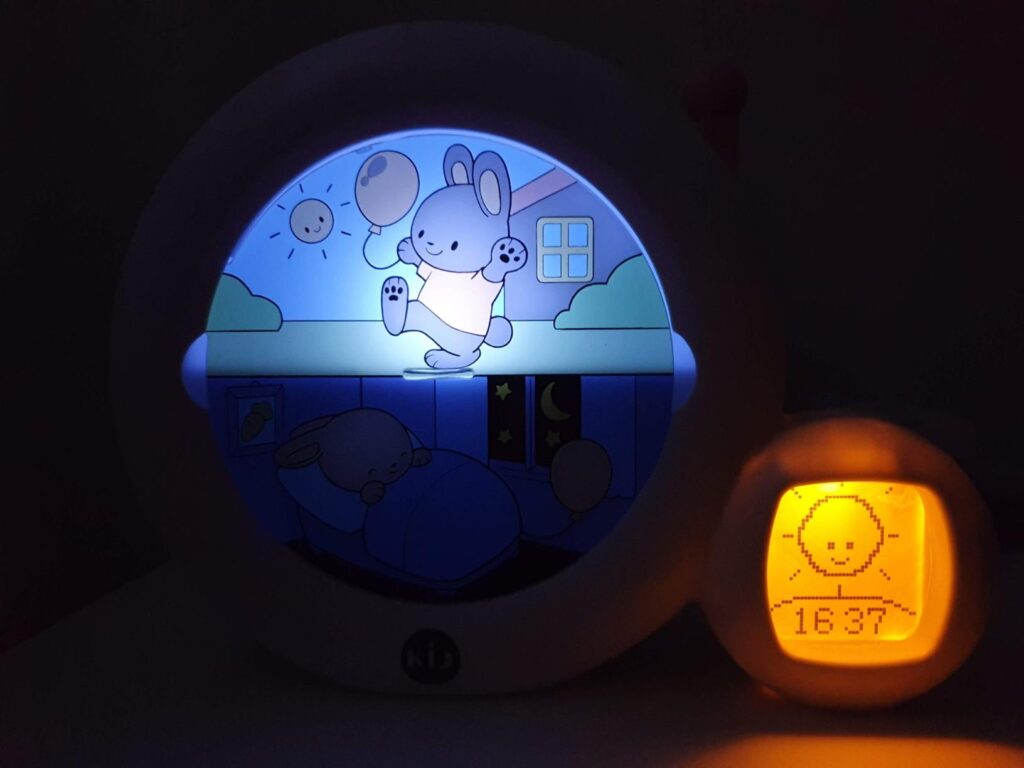 Réveil dans l'obscurité, affichant une image de lapin réveillé avec un éclairage orange, indiquant le mode jour