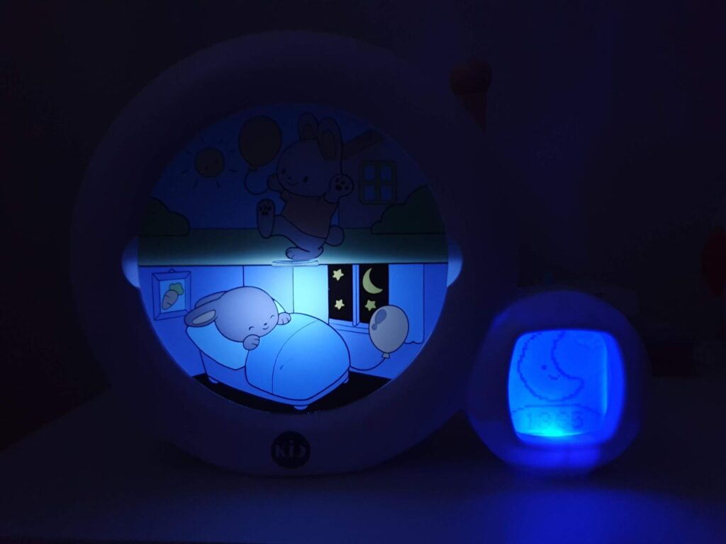Réveil dans l'obscurité, affichant une image de lapin endormi avec un éclairage bleu, indiquant le mode nuit