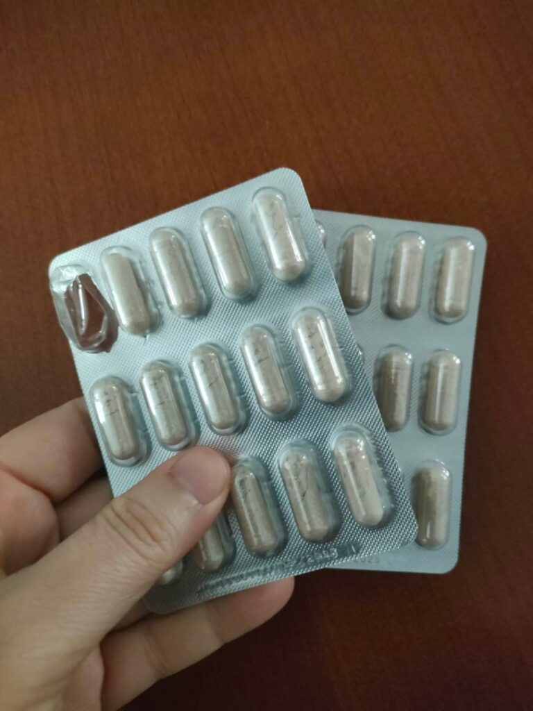 Deux plaquettes de gélules SOM-ACTIFS, dont une entamée, tenues dans une main.