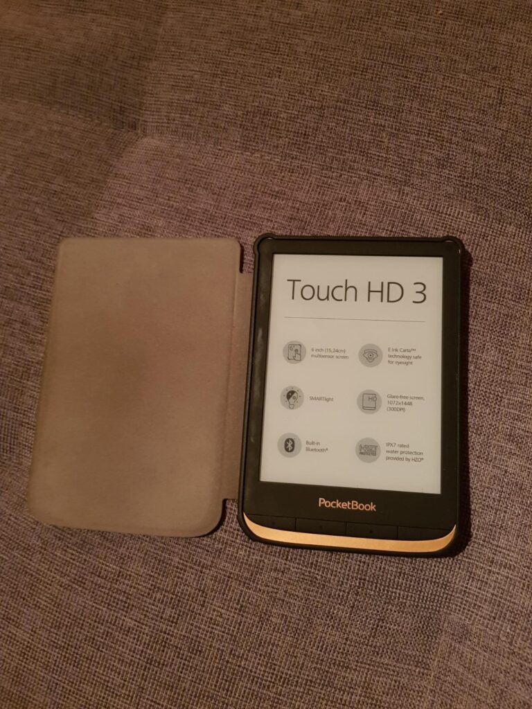 Liseuse Pocketbook Touch HD 3 avec sa coque ouverte, posée sur un tissu.