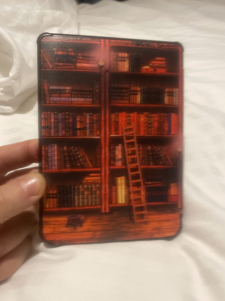 Liseuse avec coque décorée d'une bibliothèque tenue à la main, vue de face