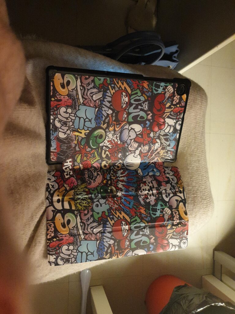 Tablette et étui avec motif graffiti, l'étui est ouvert en deux sur les genoux d'une personne