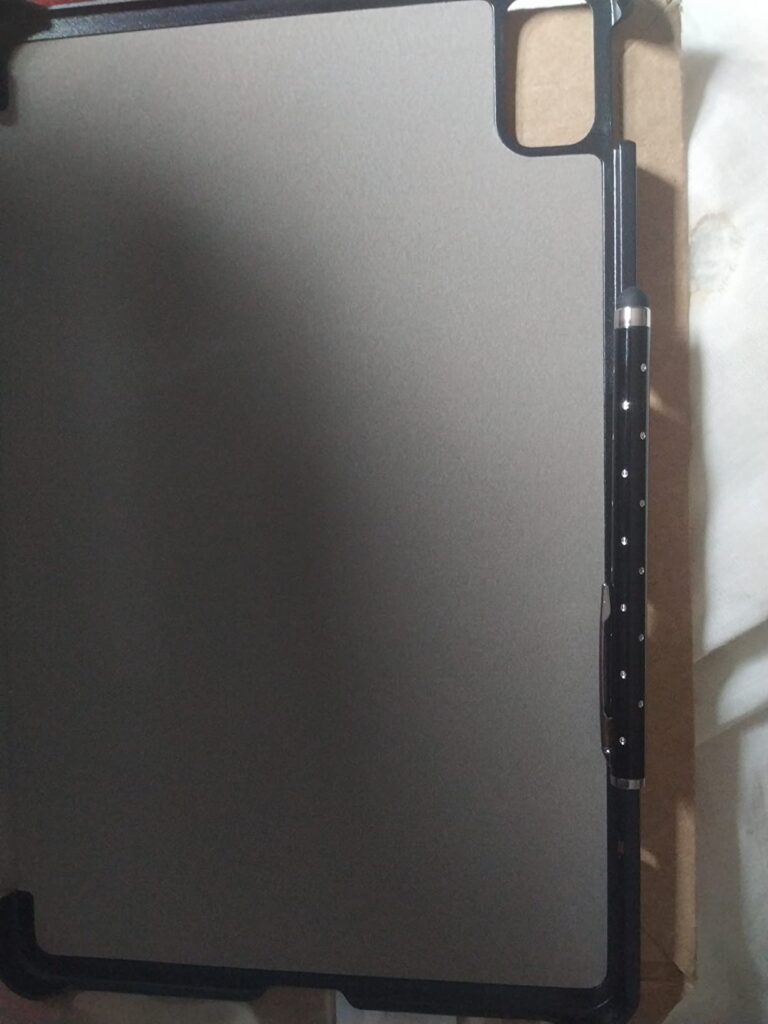 La tablette est présentée dans son étui ouvert, vue de face, sous un angle différent du visuel 4, posée sur un carton marron....