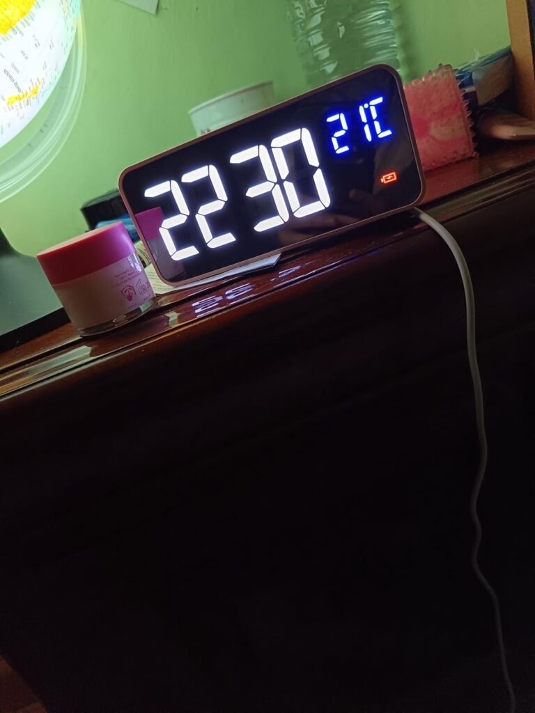 Le réveil sur une table en bois, affichant l'heure 22:30 et la température 21°C.