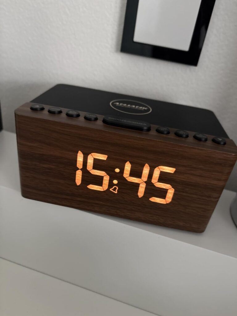 Réveil posé sur une commode, avec l'heure et l'icône de l'alarme affichées.