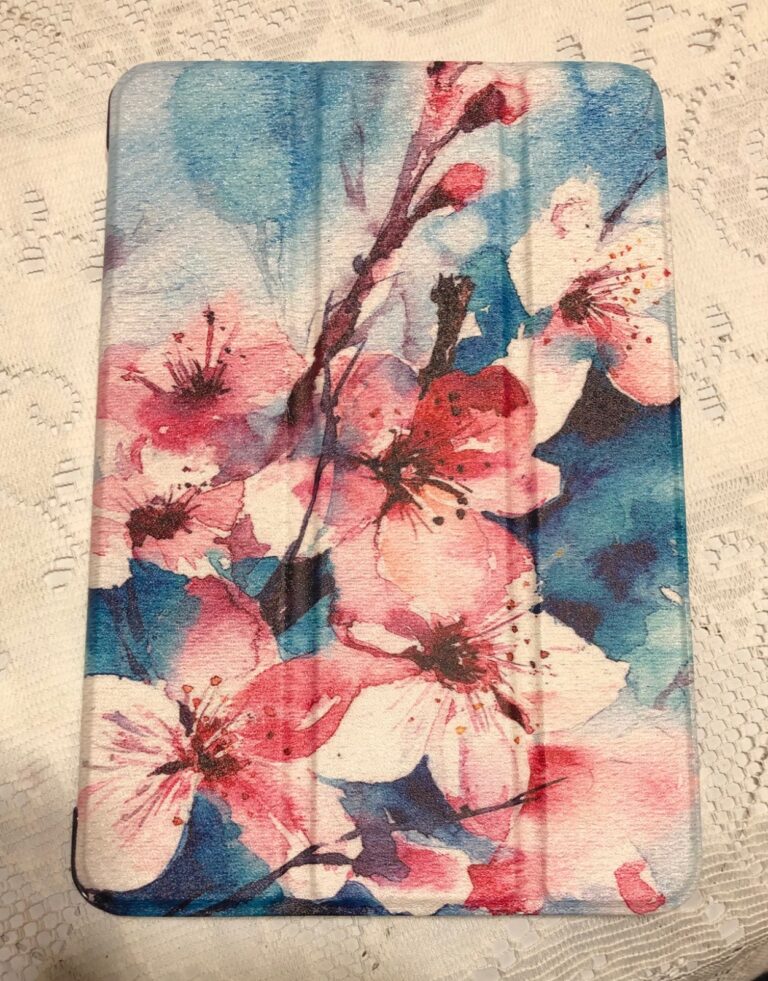Vue de dessus d'une coque de tablette fermée. La coque est illustrée de fleurs roses et de traits bleus.