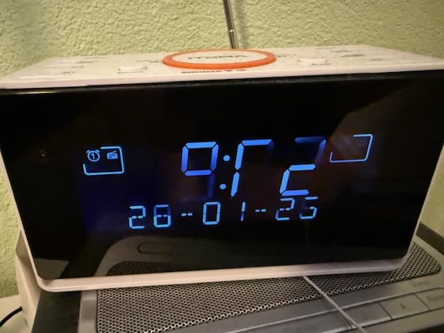 Gros plan sur l'écran du réveil, affichant l'heure, la date et des icônes d'alarme.