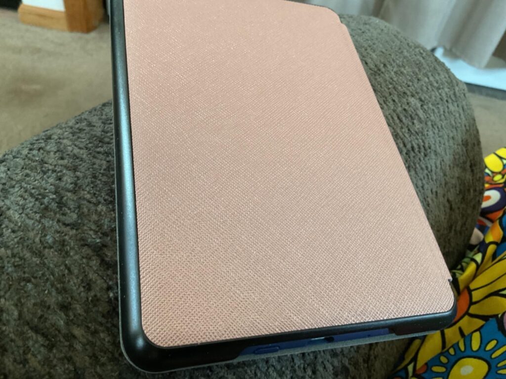 Liseuse avec une coque rose posée sur un canapé, vue de côté. C'est la même coque que le visuel 1, sous un angle différent.
