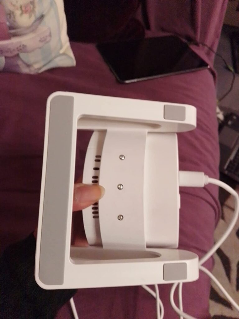 Le produit est posé à l'envers, sans l'éclairage, sur un lit avec le câble branché sur le côté.
