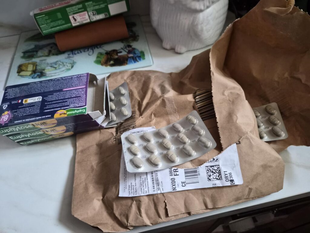 Le produit est posé sur un plan de travail avec un emballage en papier et des boîtes en carton. On y voit des plaquettes de c...