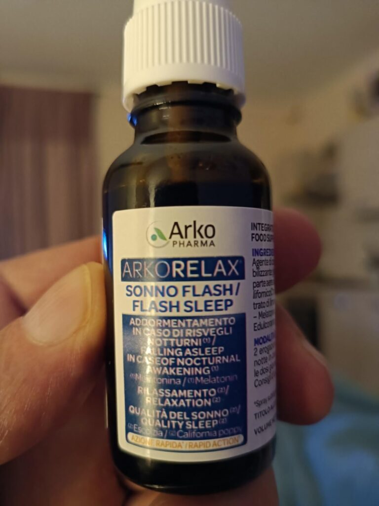 Flacon d'Arkorelax Flash Sleep tenu dans une main, avec l'étiquette orientée vers l'avant, le texte en italien et anglais est...