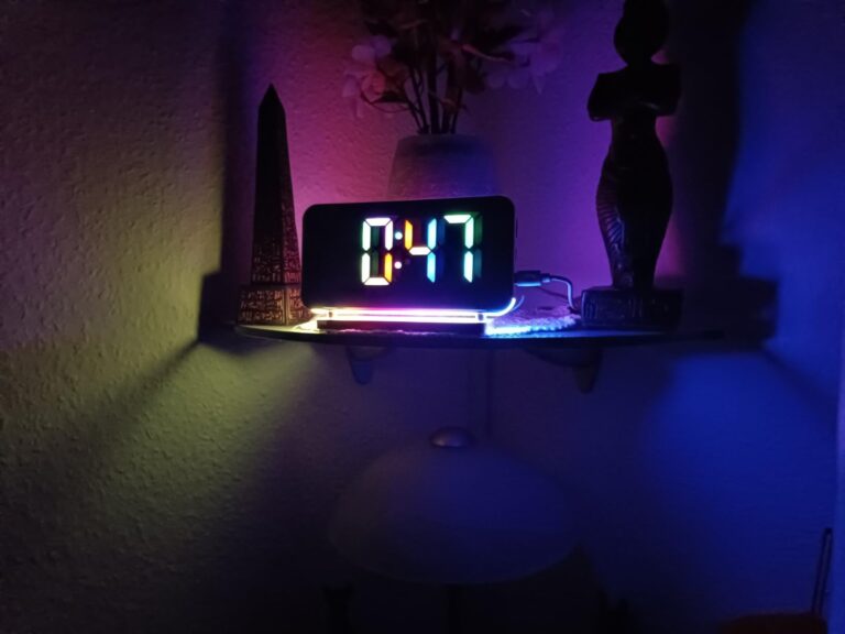 Réveil posé sur une étagère dans une pièce sombre, affichant l'heure.