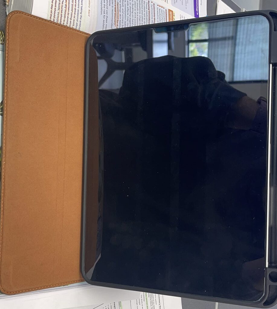 La tablette est posée avec la coque ouverte. Reflet de l'environnement sur l'écran.