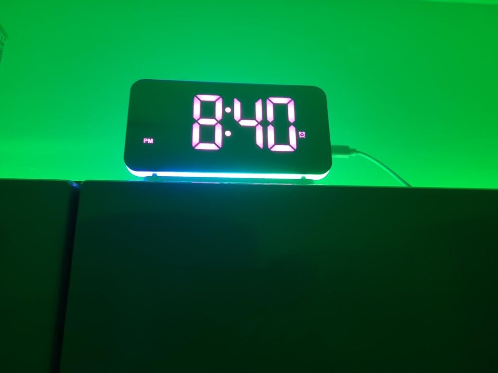 L'horloge-réveil dans l'obscurité, affichant l'heure en blanc sur fond vert clair.