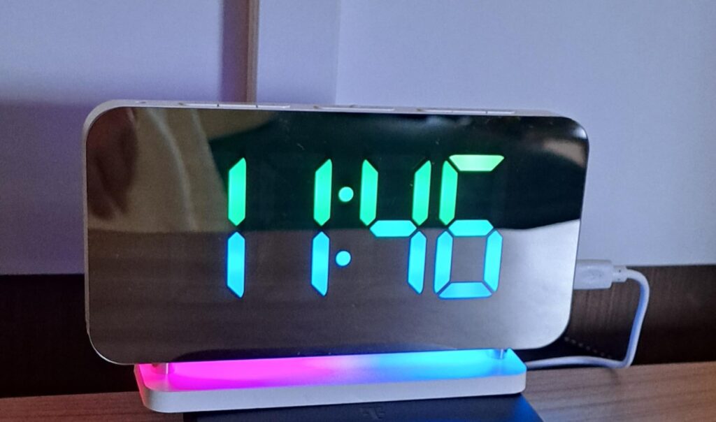 L'horloge-réveil sur un meuble, affichant l'heure. Le socle s'allume de différentes couleurs.