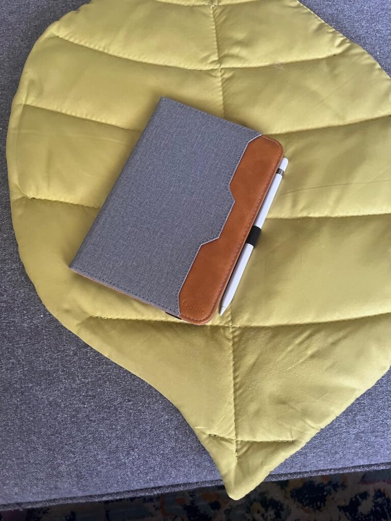 Vue de dessus d'une liseuse grise avec un stylet sur une couverture jaune en forme de feuille.