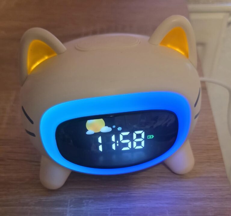 Vue frontale du réveil lumineux en forme de chat. Les oreilles s'éclairent en orange et l'écran est entouré de bleu.