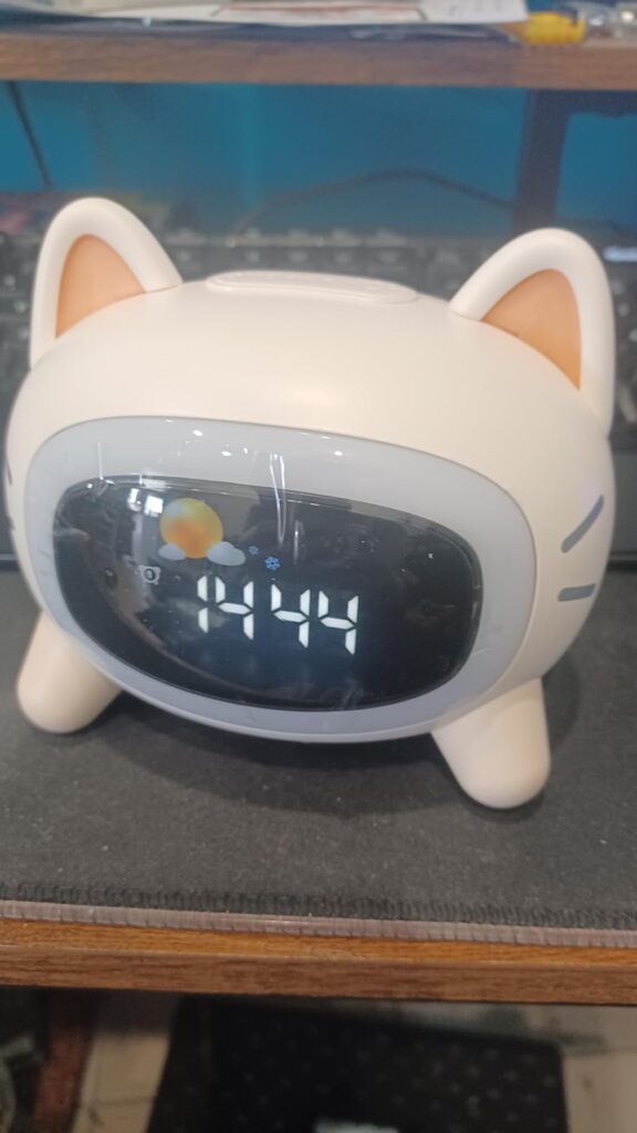 Vue frontale du réveil en forme de chat, l'écran affiche l'heure, sans éclairage d'ambiance.