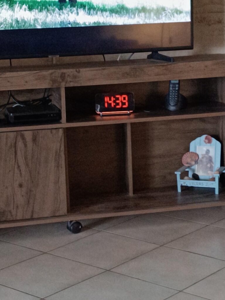 Le radio-réveil sur un meuble TV. L'affichage est rouge.