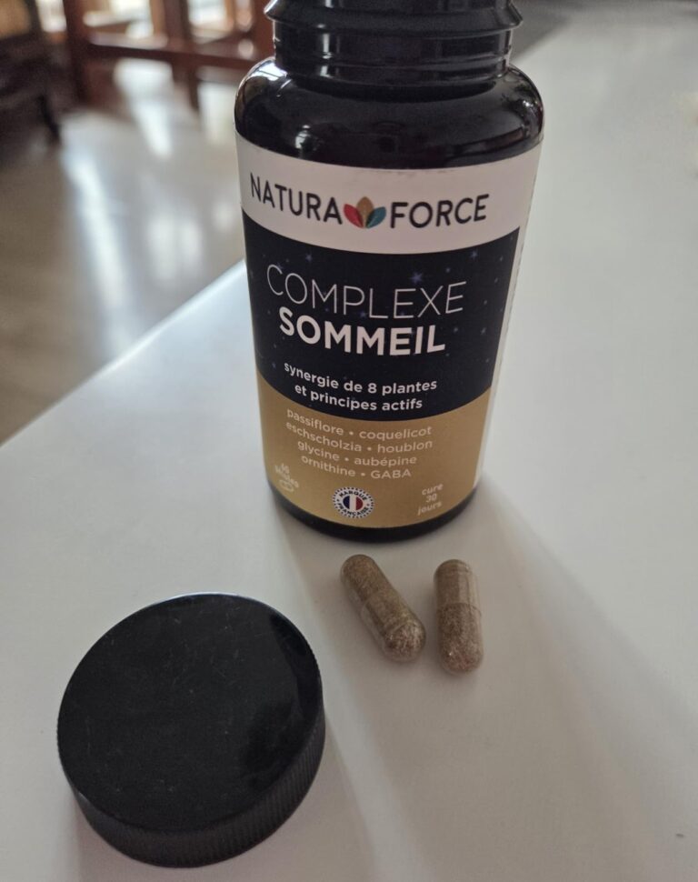 Flacon du complément alimentaire Complexe Sommeil de Natura Force avec deux gélules posées à côté. Le bouchon est également p...
