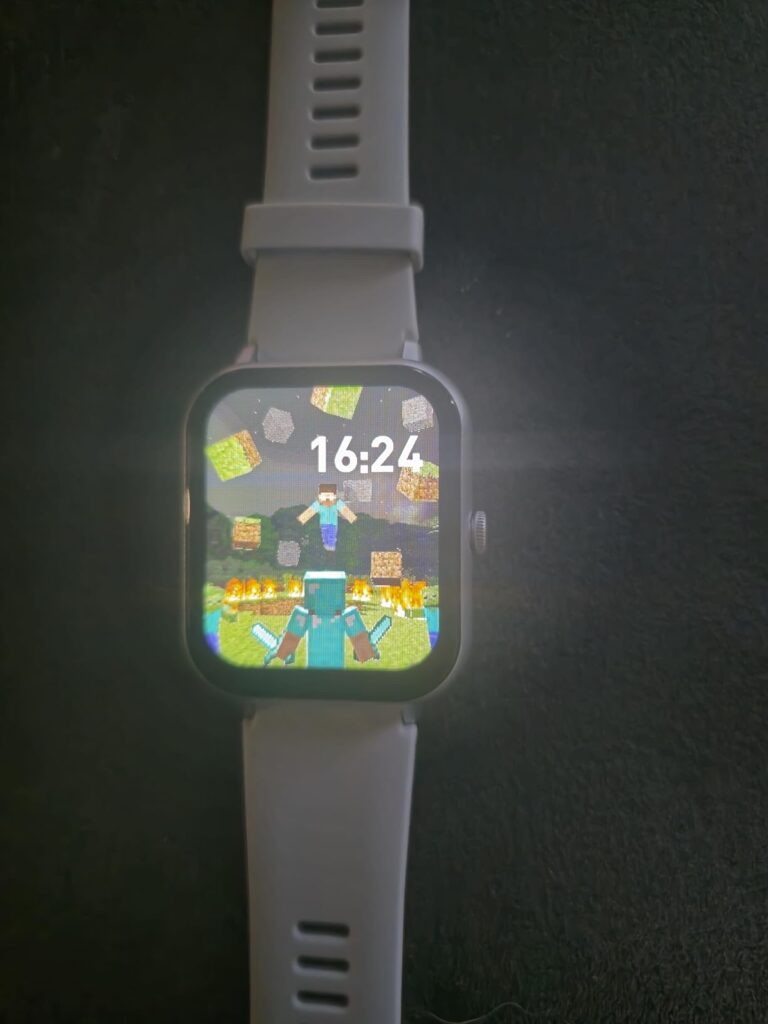 Montre connectée grise sur fond noir, affichant une scène de jeu vidéo. Très similaire au visuel 1.