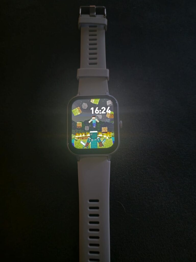 Montre connectée grise sur fond noir, affichant une scène de jeu vidéo. Très similaire au visuel 0.