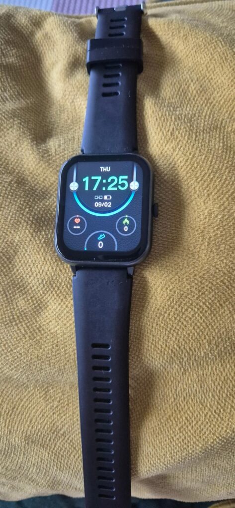 Montre connectée noire sur un tissu jaune, affichant l'heure et des icônes.