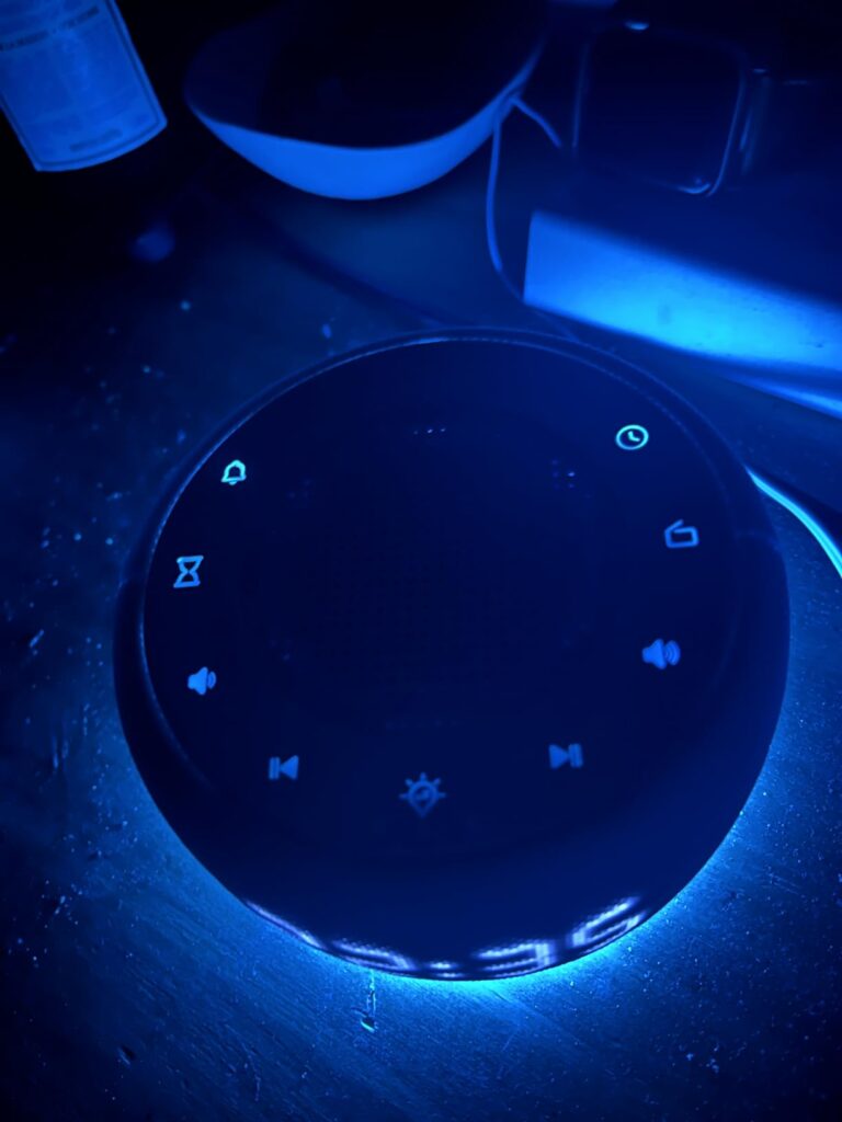 Vue de dessus du réveil, lumière éteinte. Les icônes des boutons sont visibles en bleu.