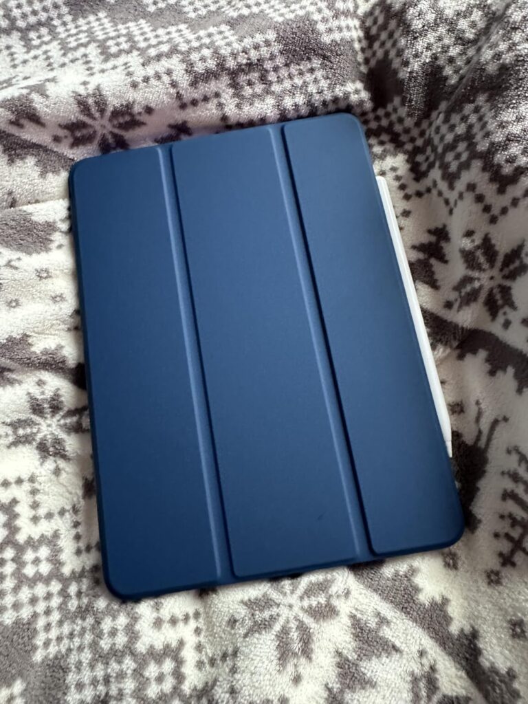 Vue de face de la coque de protection pour iPad Mini 6, couleur bleue, sur un plaid avec des motifs d'étoiles et de flocons....