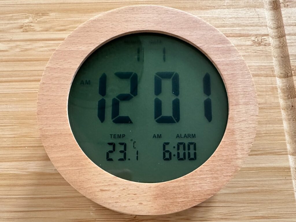 Vue de face du réveil avec affichage de l'heure, de la température et de l'alarme, sur fond vert.