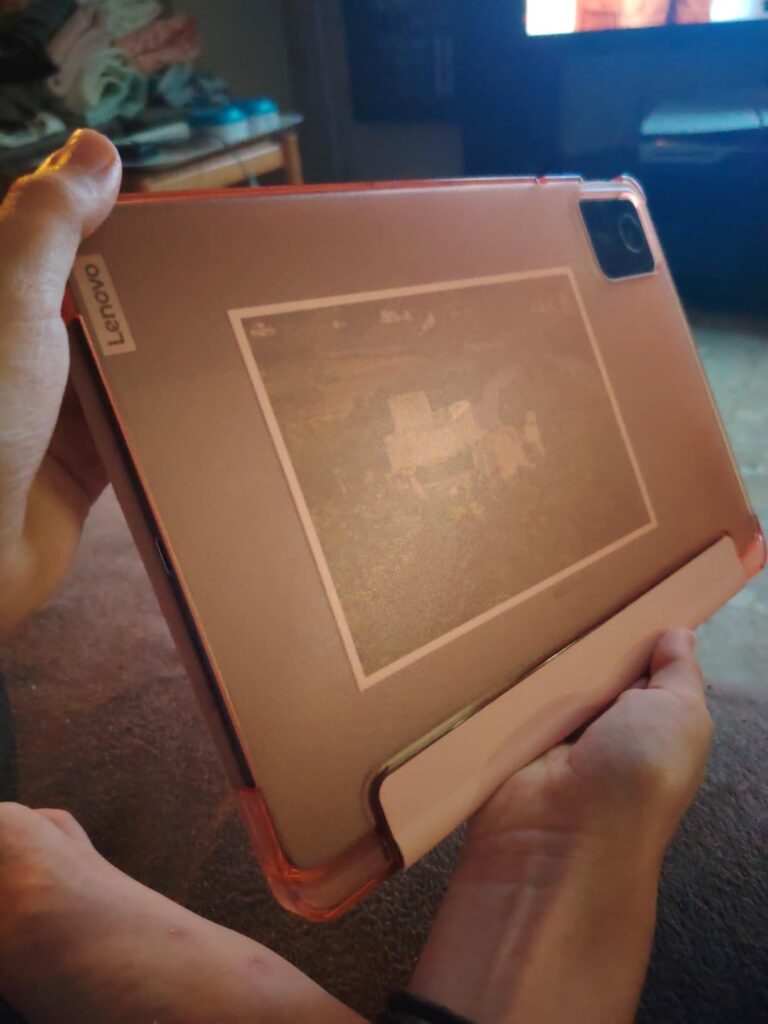 La tablette avec la coque de protection rose est tenue en main, la tablette est affichée en mode paysage avec un fond flou qu...