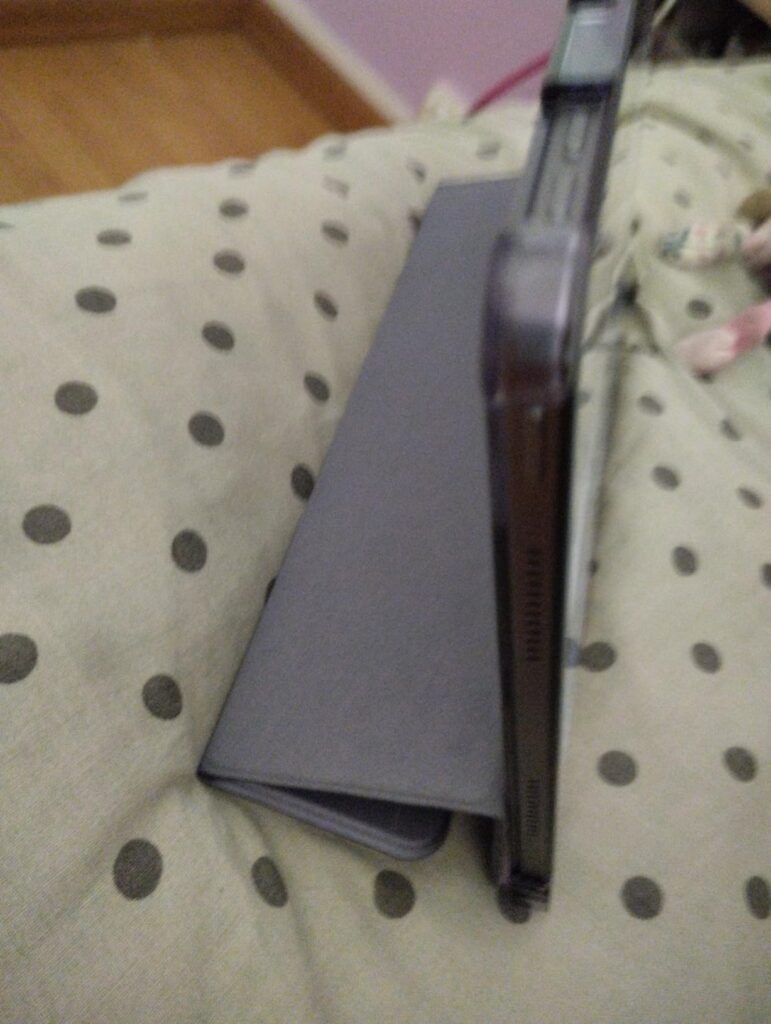 La tablette avec la coque est posée sur une surface, montrant le profil et l'inclinaison de la coque en mode support.