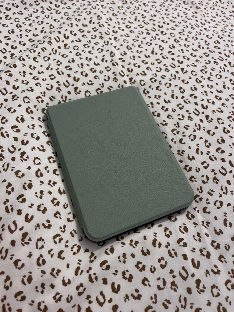 Liseuse Kobo avec une coque verte sur un tissu imprimé léopard, vue de dessus, coque fermée.