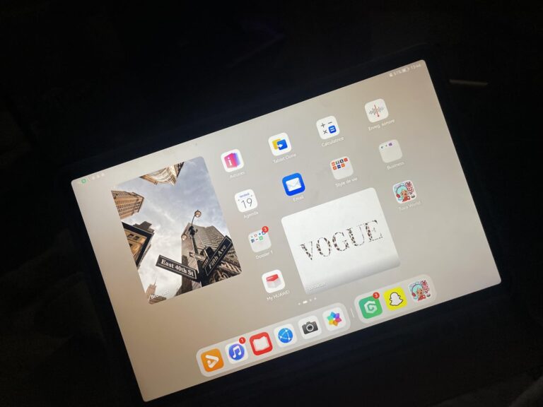 Tablette iPad allumée sur fond noir, affichant des applications et une image de couverture de Vogue.