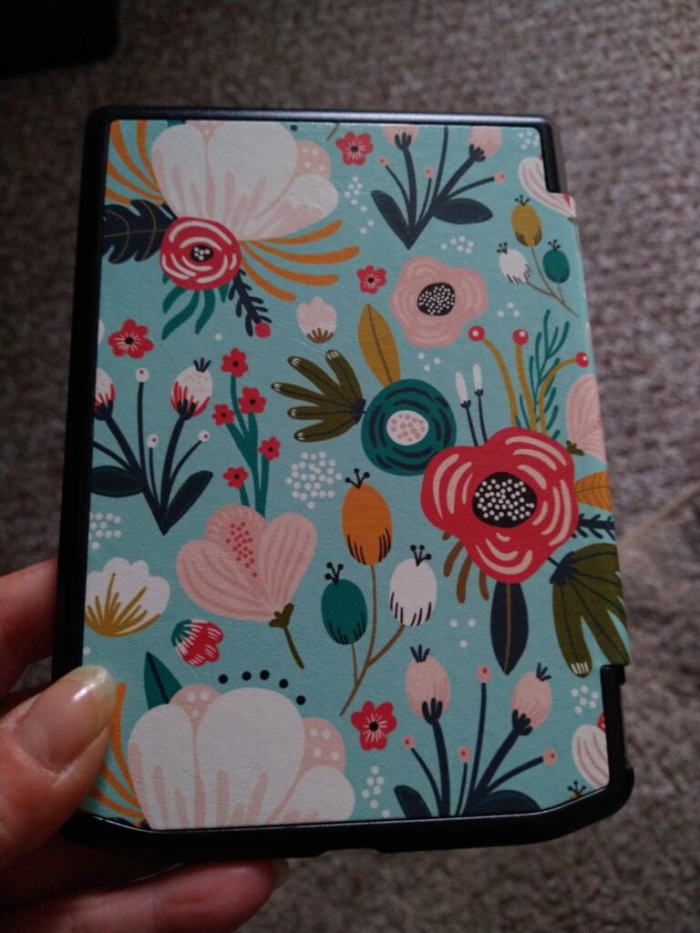 Vue de dessus de la coque de protection fermée, avec un motif floral coloré. La main de l'utilisateur est visible en bas de l...