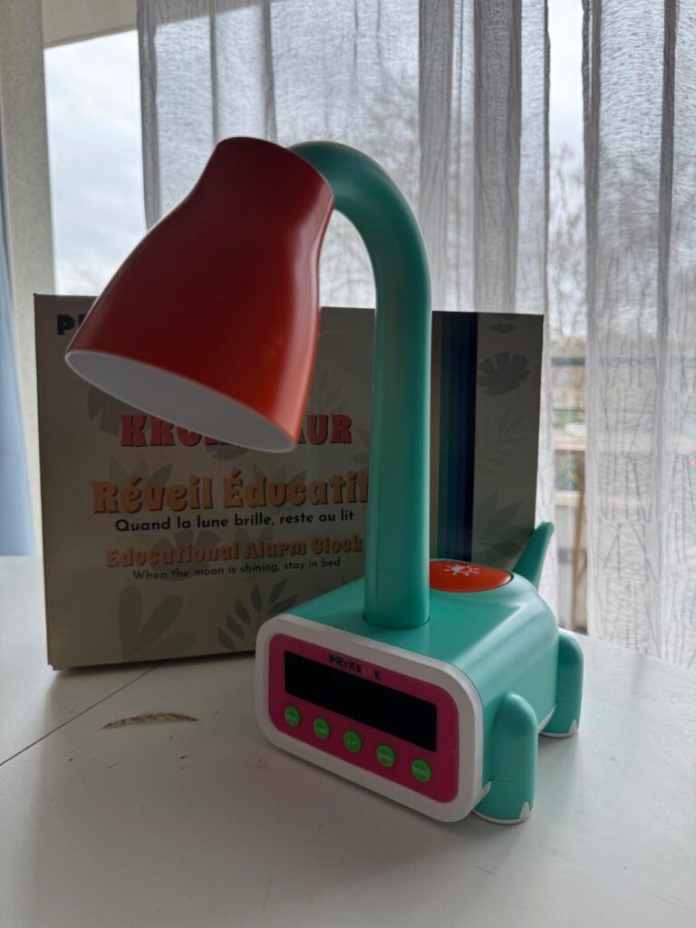 La lampe est posée sur une table. Le carton est posé derrière la lampe.