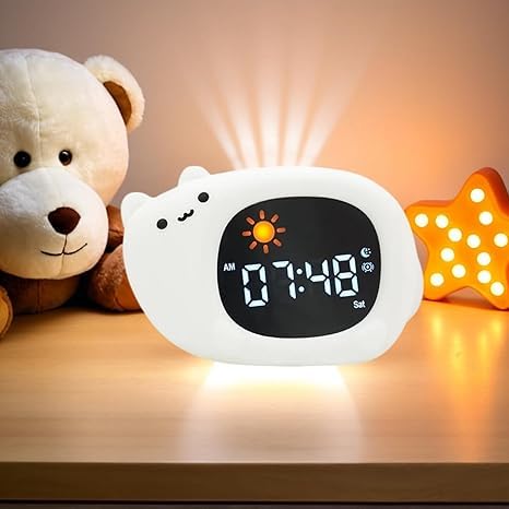 Réveil chat blanc posé sur une table de chevet, avec un nounours et une étoile lumineuse