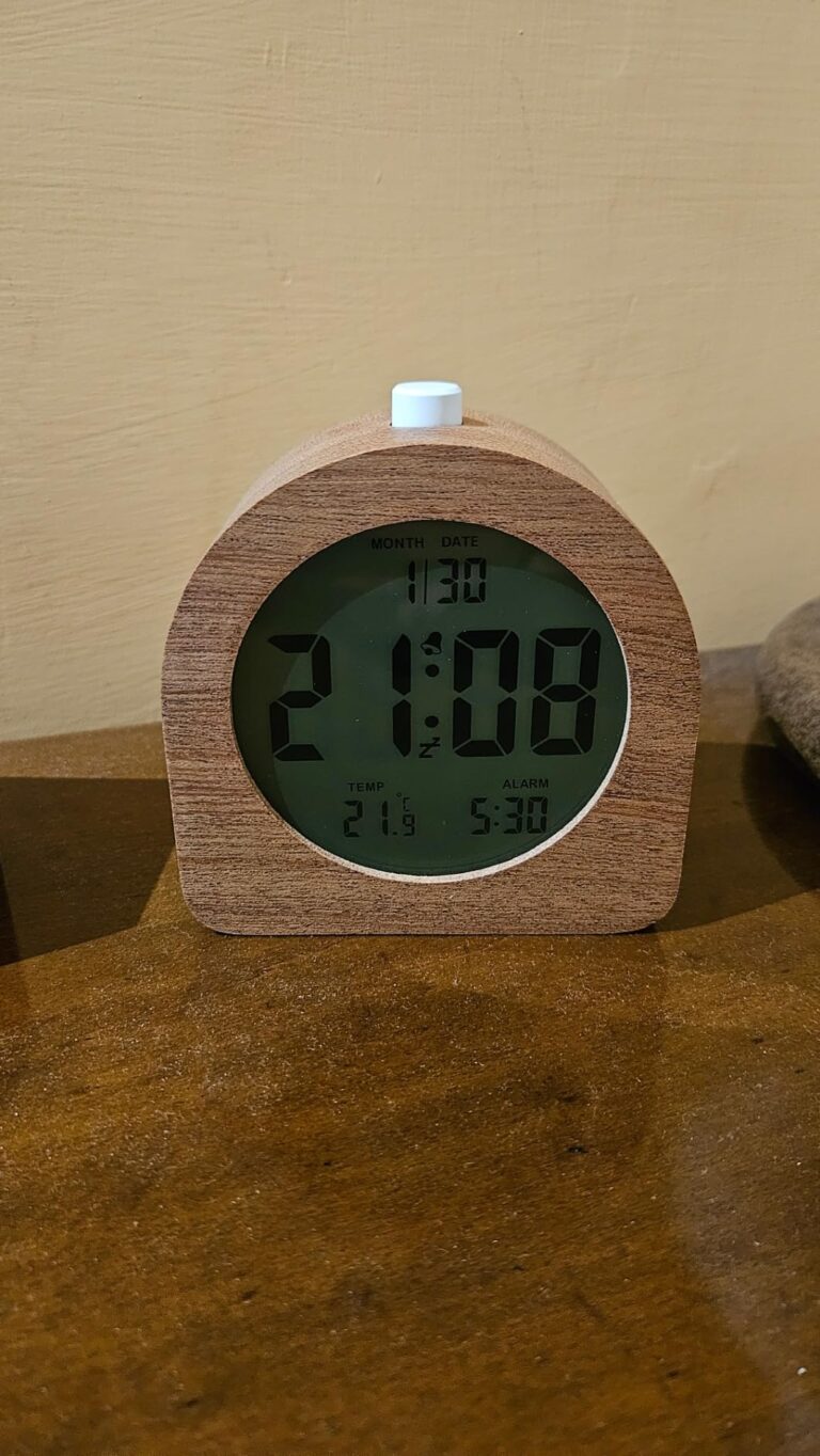 Un réveil en bois avec un écran numérique affichant l'heure, la date et la température. Il est posé sur une table en bois.