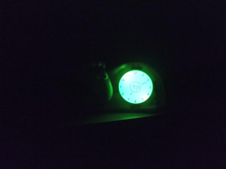 Réveil de jour pour enfant, vu dans l'obscurité, l'écran est illuminé. Il n'y a pas d'autres objets autour.