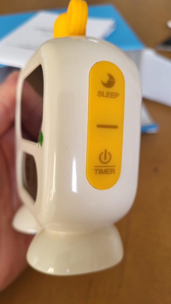 Vue latérale du réveil robot avec les boutons de réglage. Les boutons sont un croissant de lune avec le texte "SLEEP", un sym...
