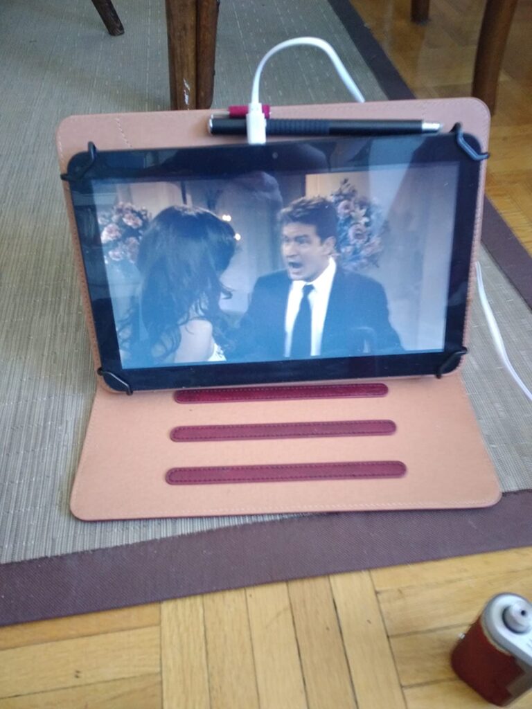 Tablette avec une vidéo affichée, posée sur une table basse, avec un stylet branché sur le côté.