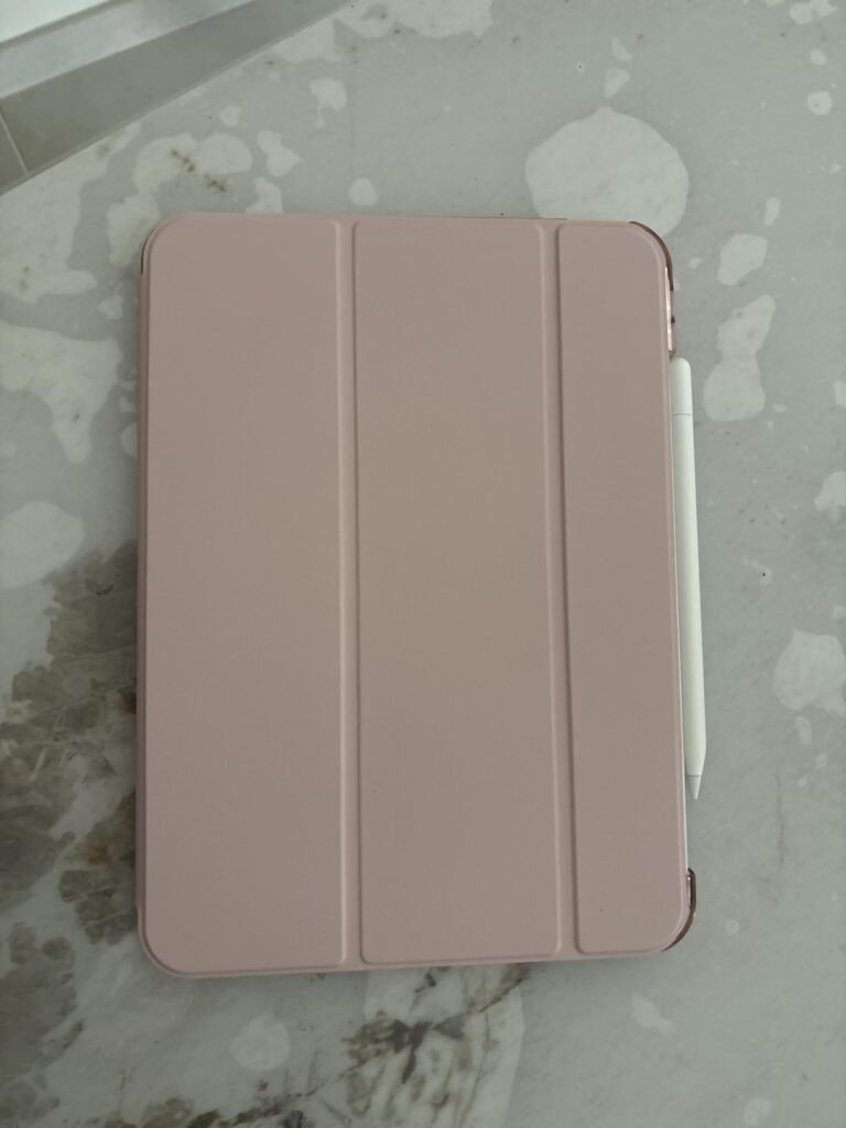 Vue de dessus d'une tablette iPad Mini 6e génération, de couleur rose doré, protégée par une coque-clavier de couleur rose. U...