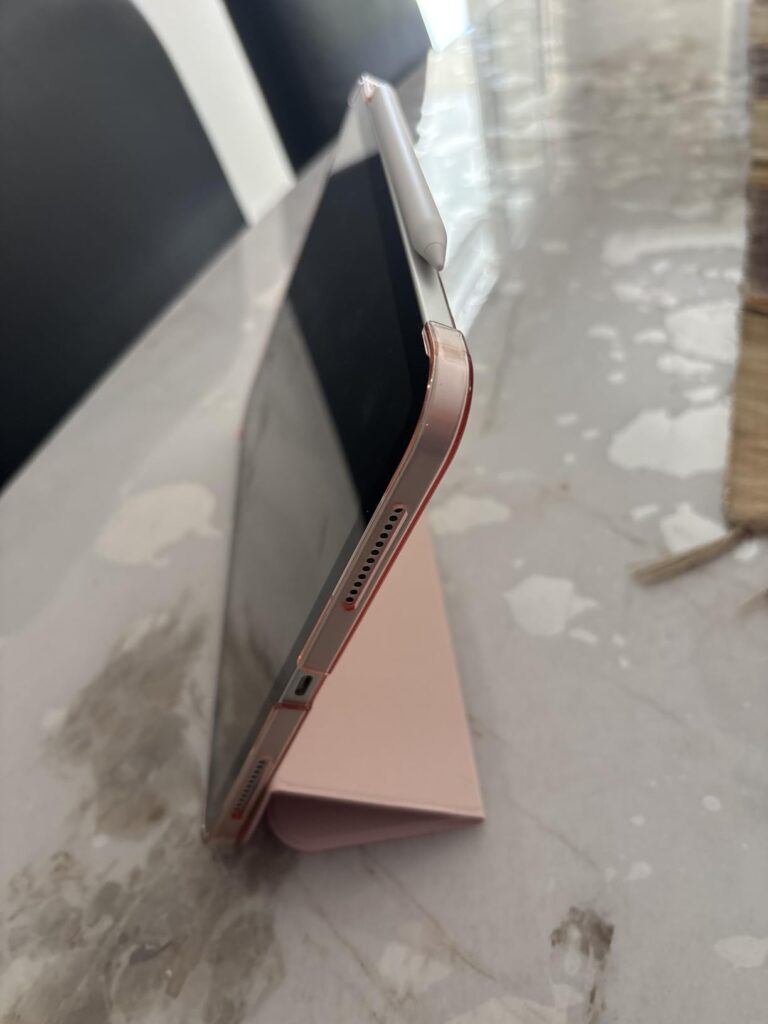 Vue latérale d'une tablette iPad Mini 6e génération, de couleur rose doré, protégée par une coque-clavier de couleur rose. La...