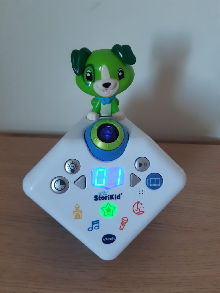 Le boîtier du projecteur de son et lumière, avec une figurine de chien vert sur le dessus, et des icônes sur le boîtier